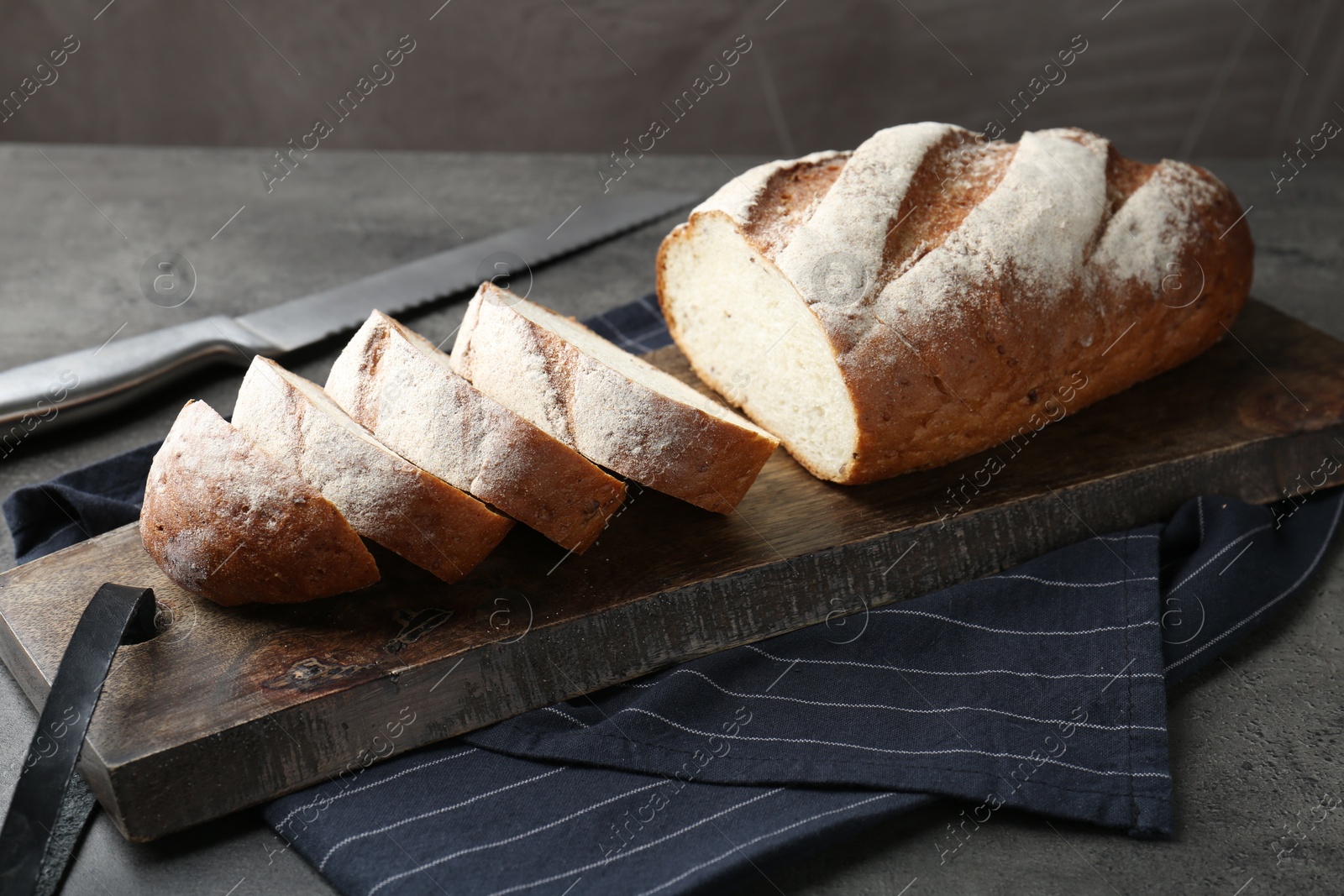 Photo of Cutting board with fresh bread on grey table