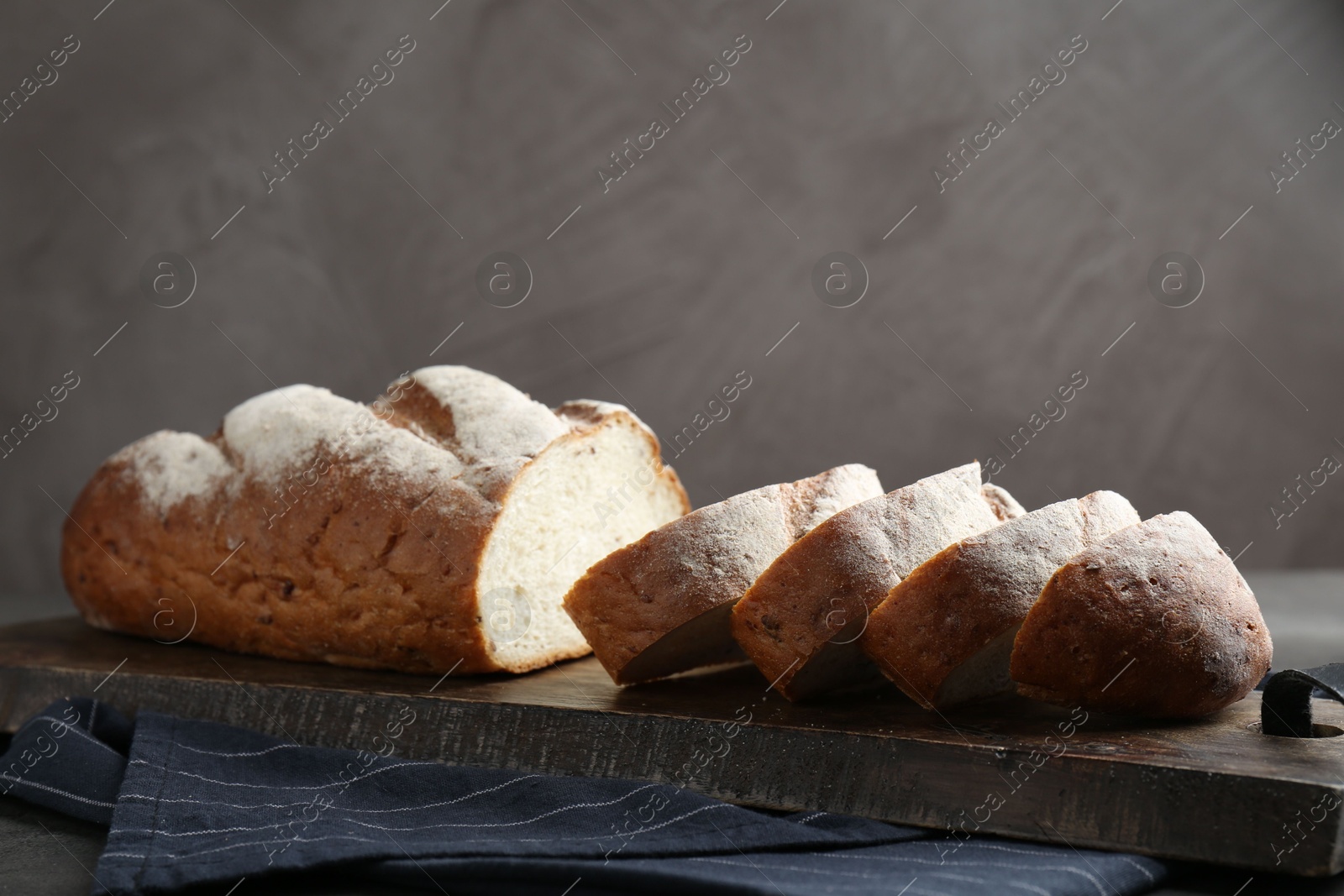 Photo of Cutting board with fresh bread on grey table. Space for text