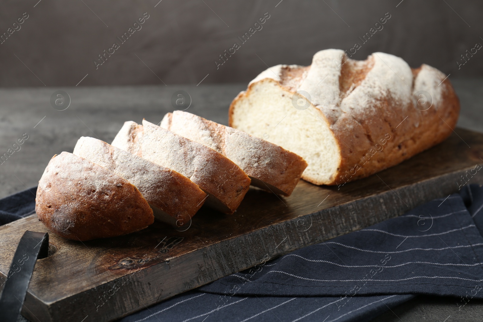 Photo of Cutting board with fresh bread on grey table, closeup