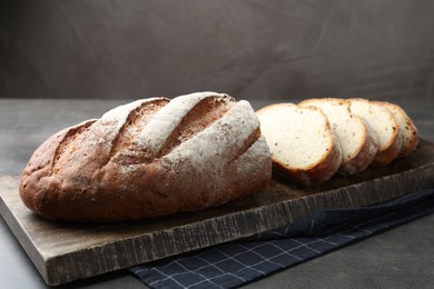 Photo of Cutting board with fresh bread on grey table, closeup