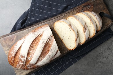 Photo of Cutting board with fresh bread on grey table, top view