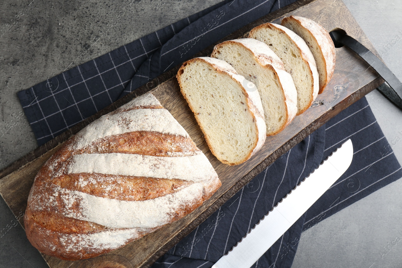 Photo of Cutting board with fresh bread and knife on grey table, top view