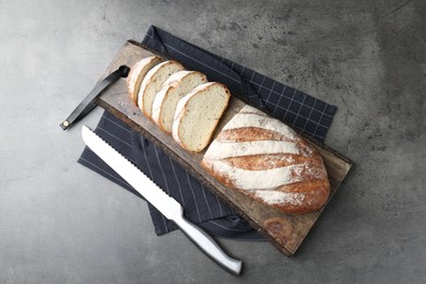 Photo of Cutting board with fresh bread and knife on grey table, top view