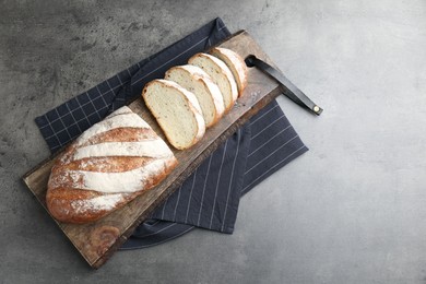 Photo of Cutting board with fresh bread on grey table, top view