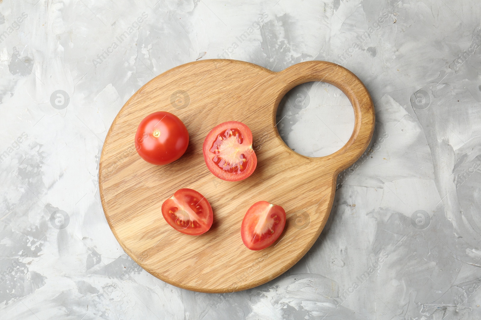 Photo of Cutting board with tomatoes on grey textured table, top view