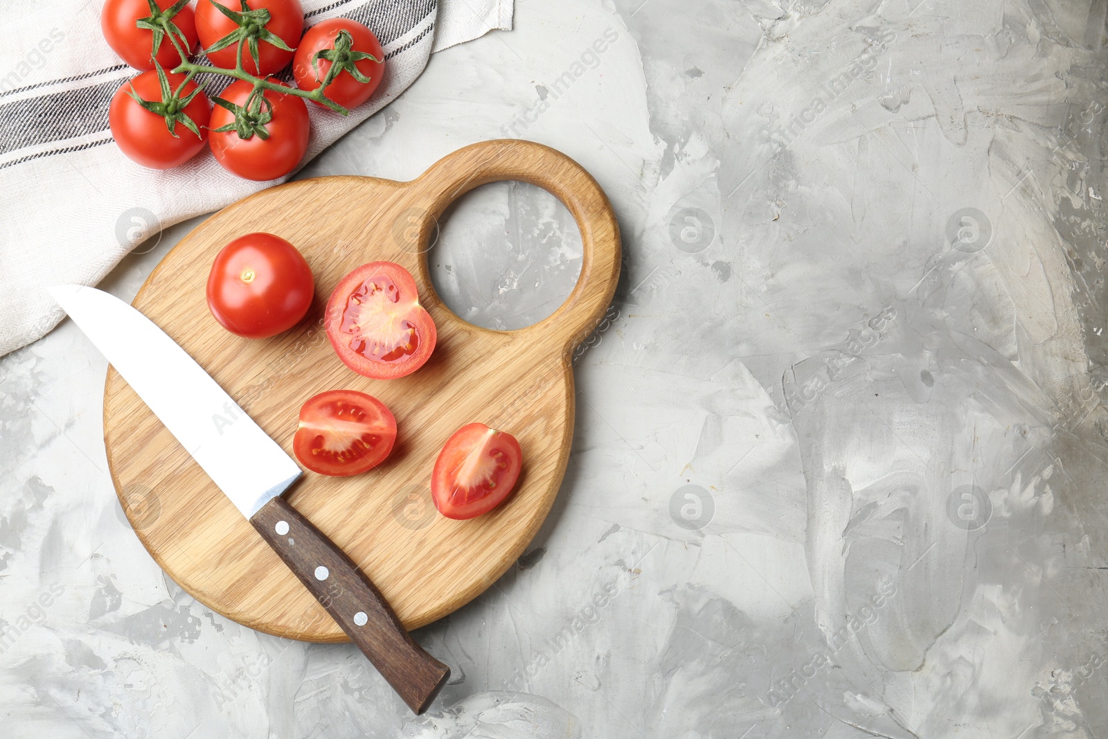 Photo of Cutting board with tomatoes and knife on grey textured table, flat lay. Space for text