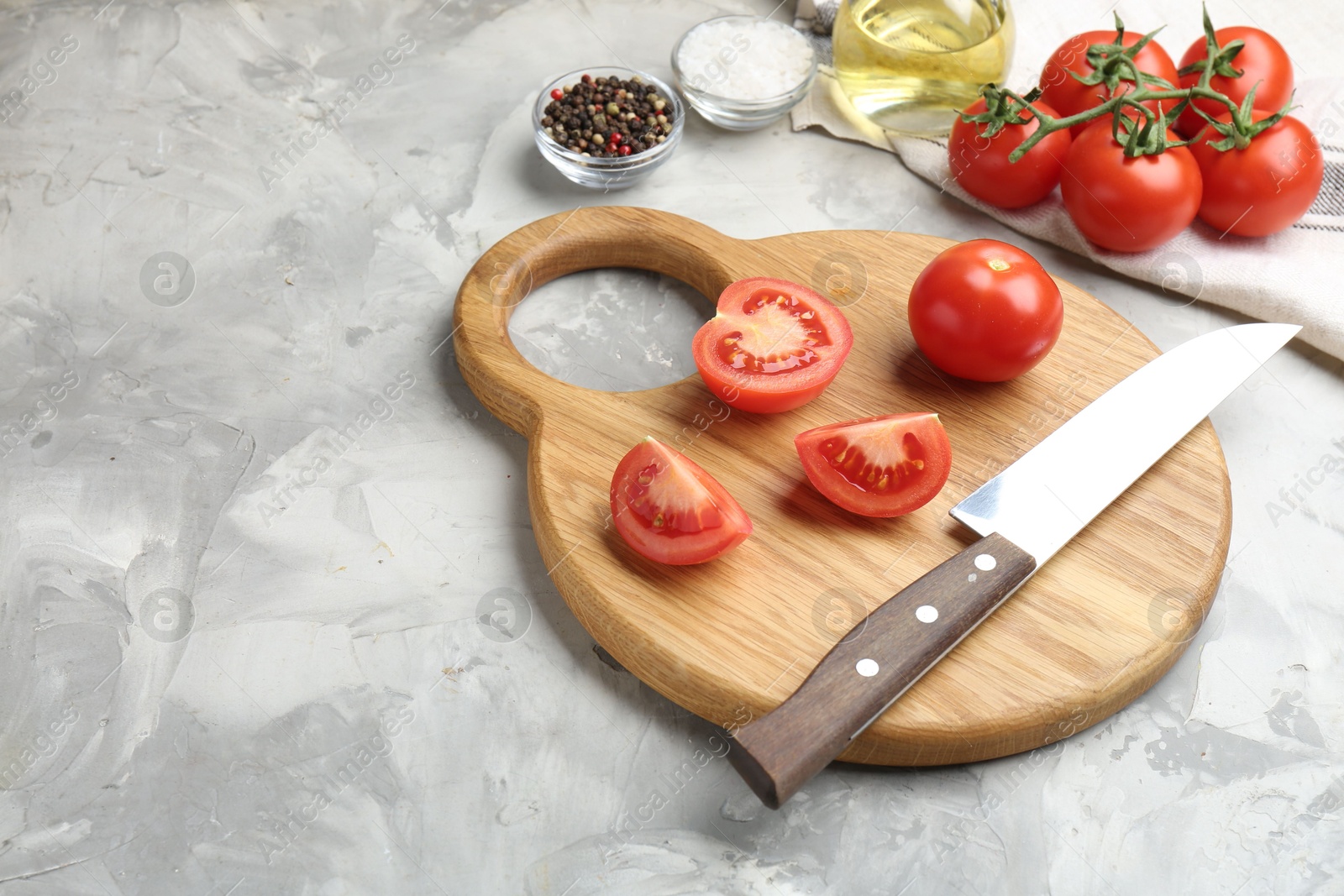 Photo of Cutting board with knife, tomatoes and spices on grey textured table, closeup. Space for text