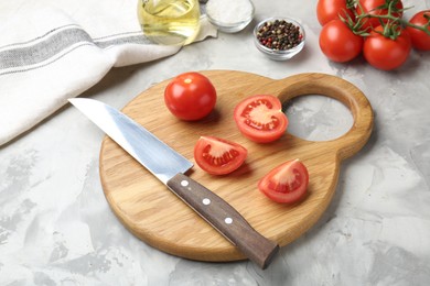 Photo of Cutting board with knife, tomatoes and spices on grey textured table, closeup