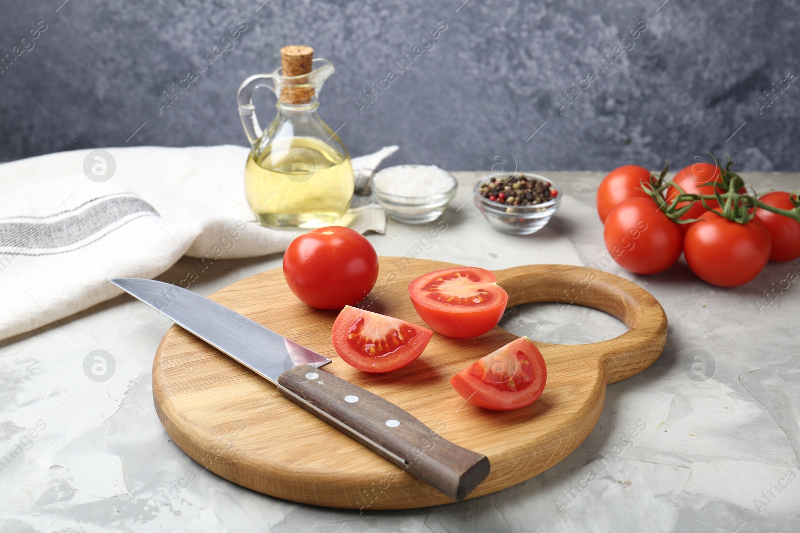 Photo of Cutting board with knife, tomatoes and spices on grey textured table, closeup