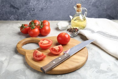 Photo of Cutting board with knife, tomatoes and spices on grey textured table, closeup