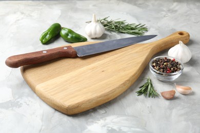 Photo of Cutting board with knife and spices on grey textured table, closeup