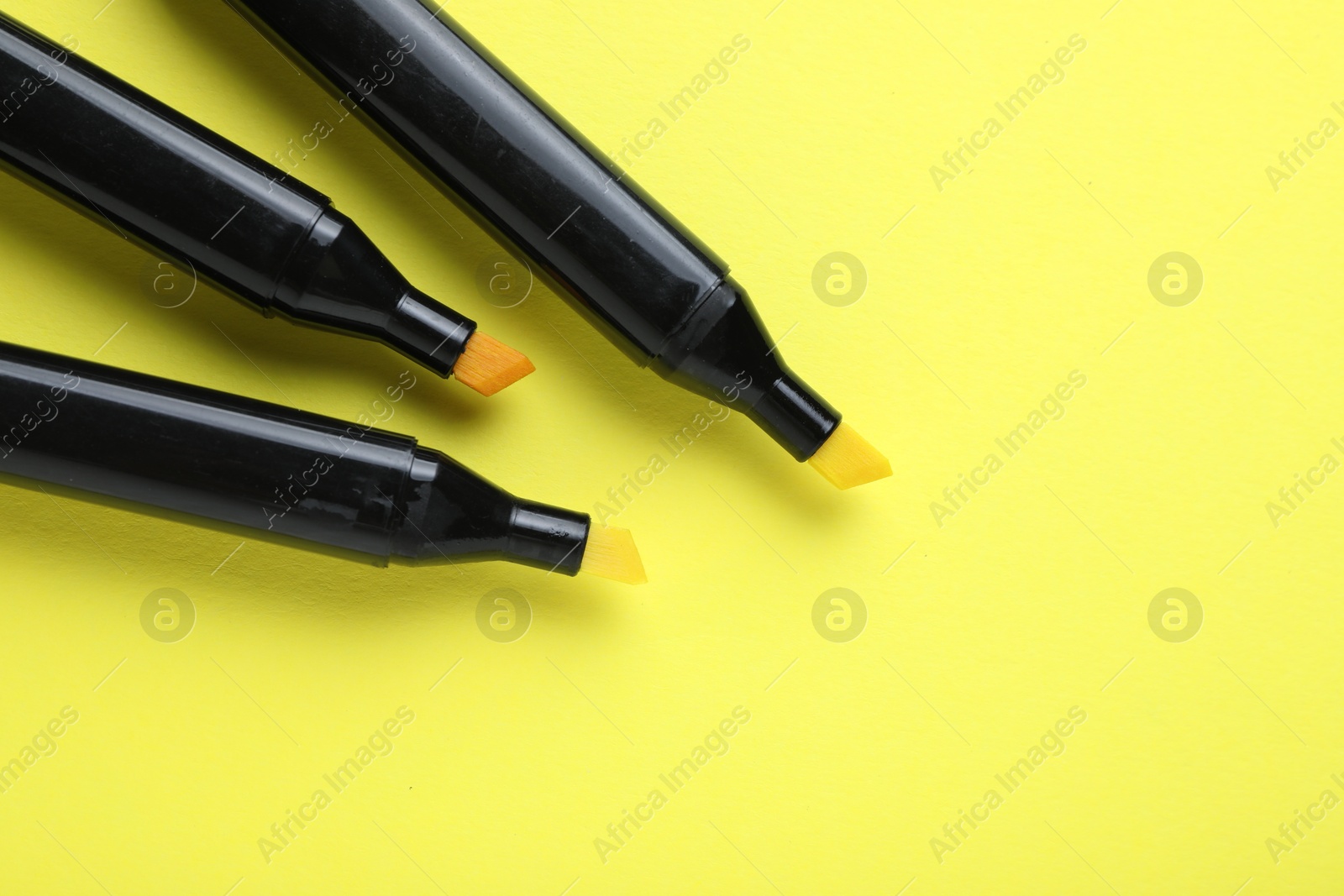 Photo of Color double sided markers on yellow background, top view. Space for text