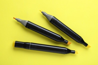 Photo of Color double sided markers on yellow background, top view