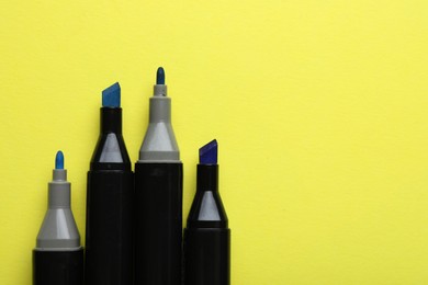 Photo of Color double sided markers on yellow background, top view. Space for text