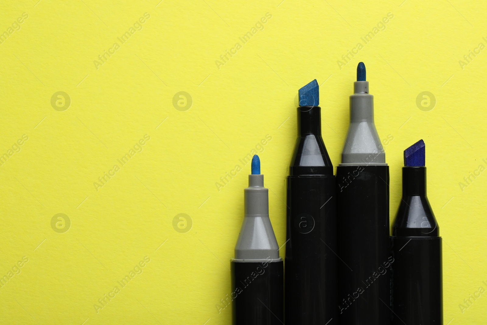 Photo of Color double sided markers on yellow background, top view. Space for text