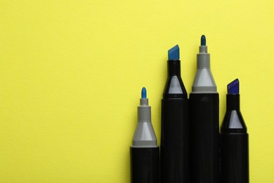 Photo of Color double sided markers on yellow background, top view. Space for text