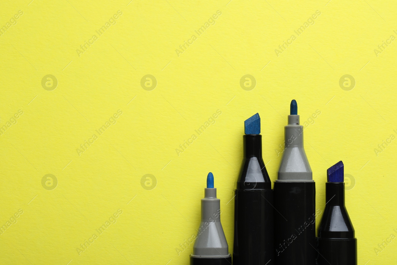 Photo of Color double sided markers on yellow background, top view. Space for text