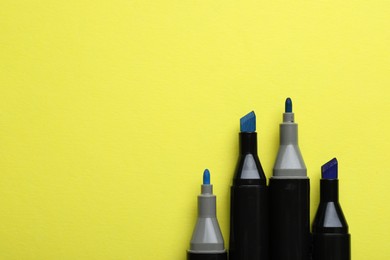 Photo of Color double sided markers on yellow background, top view. Space for text