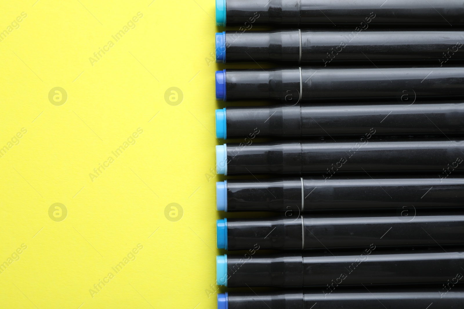 Photo of Color double sided markers on yellow background, top view. Space for text