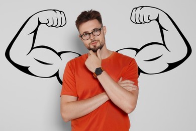 Image of Handsome man with drawing of strong arms behind him on light grey background