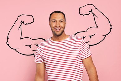 Image of Handsome young man with drawing of strong arms behind him on pink background