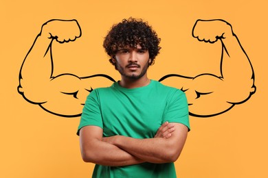 Handsome young man with drawing of strong arms behind him on orange background