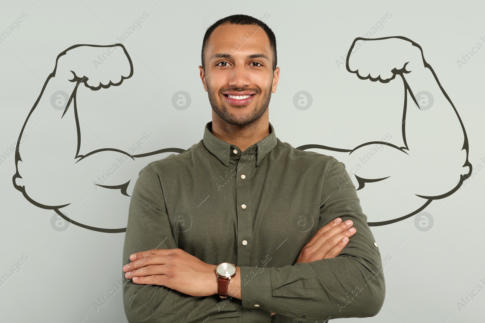 Image of Handsome young man with drawing of strong arms behind him on grey background