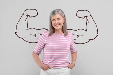 Image of Beautiful mature woman with drawing of strong arms behind her on grey background