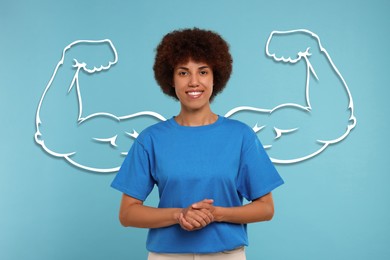 Beautiful woman with drawing of strong arms behind her on light blue background