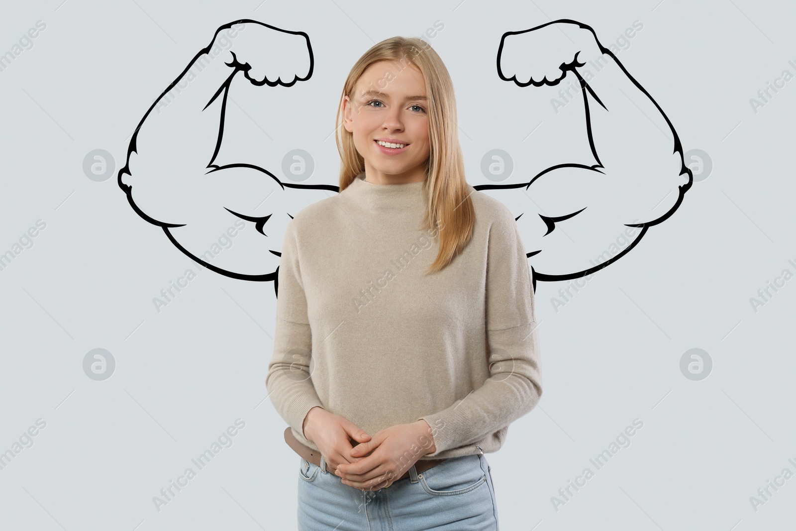 Image of Beautiful young woman with drawing of strong arms behind her on light grey background