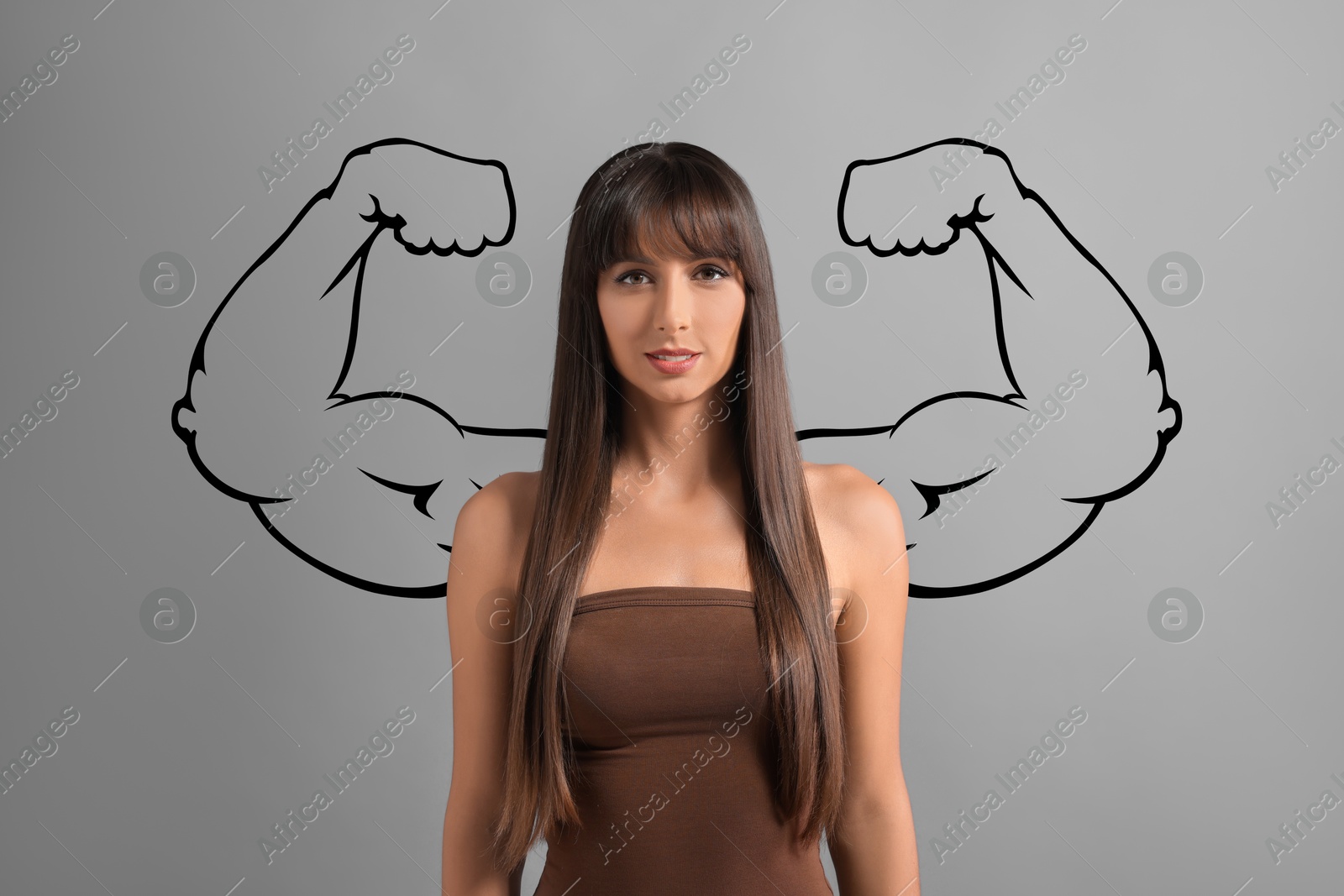 Image of Confident beautiful woman with drawing of strong arms behind her on grey background