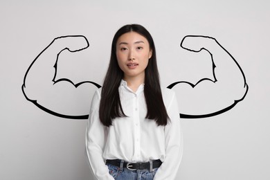 Image of Beautiful woman with drawing of strong arms behind her on light grey background