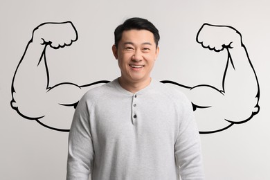 Image of Happy man with drawing of strong arms behind him on grey background