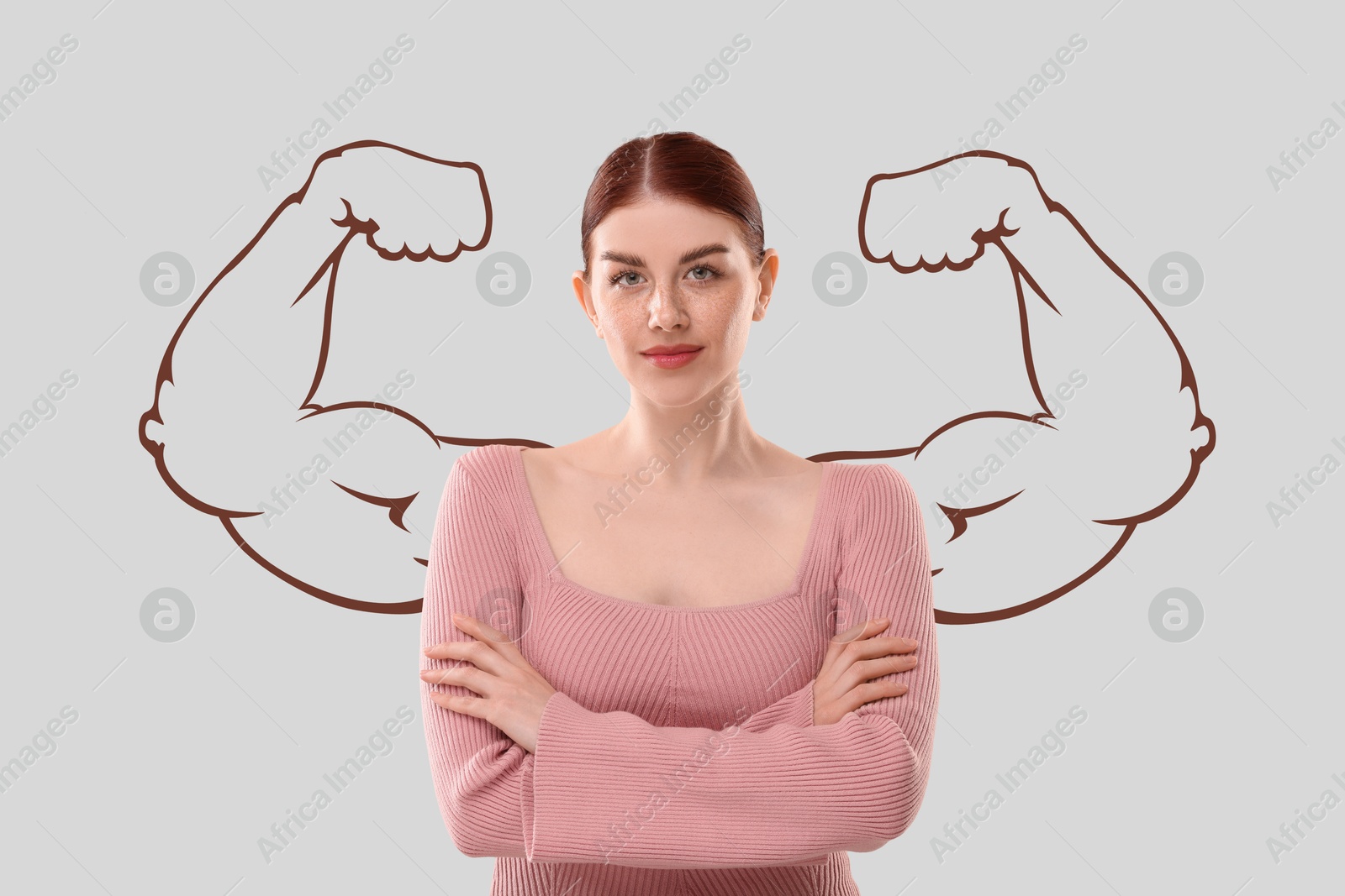 Image of Confident beautiful woman with drawing of strong arms behind her on light grey background