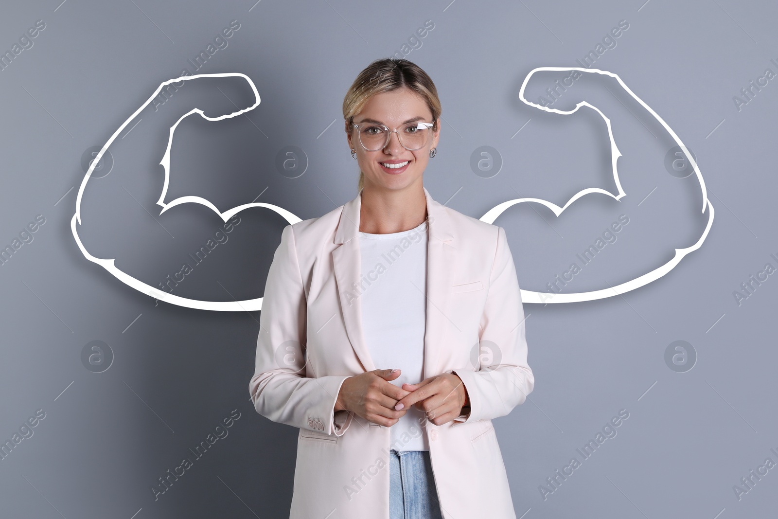 Image of Confident beautiful woman with drawing of strong arms behind her on grey background