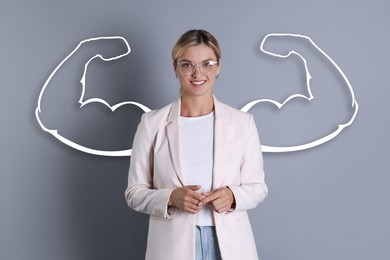 Image of Confident beautiful woman with drawing of strong arms behind her on grey background