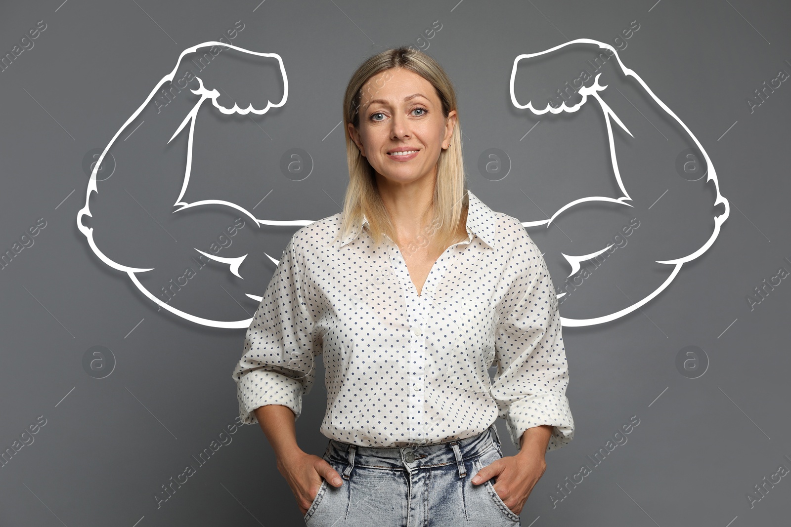 Image of Confident beautiful woman with drawing of strong arms behind her on grey background