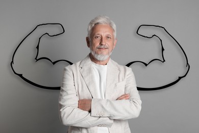 Image of Confident senior businessman with drawing of strong arms behind him on grey background