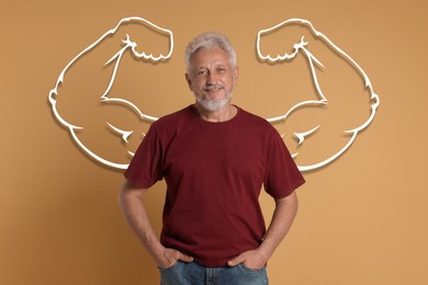 Image of Confident senior man with drawing of strong arms behind him on dark beige background