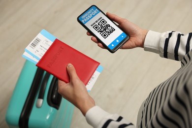 Image of Tourist with passport, flight tickets and mobile phone indoors, above view. Immunity passport app with QR code on device screen