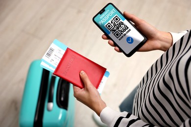 Image of Tourist with passport, flight tickets and mobile phone indoors, above view. Immunity passport app with QR code on device screen