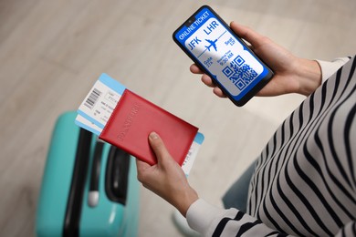 Image of Tourist with passport, flight tickets and mobile phone indoors, above view. Online ticket with QR code on device screen