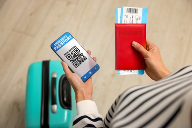 Image of Tourist with passport, flight tickets and mobile phone indoors, above view. Immunity passport app with QR code on device screen