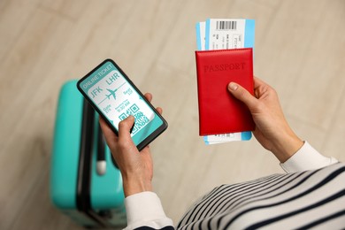 Image of Tourist with passport, flight tickets and mobile phone indoors, above view. Online ticket with QR code on device screen