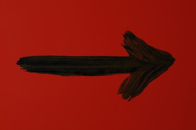 Image of One black painted arrow on red background