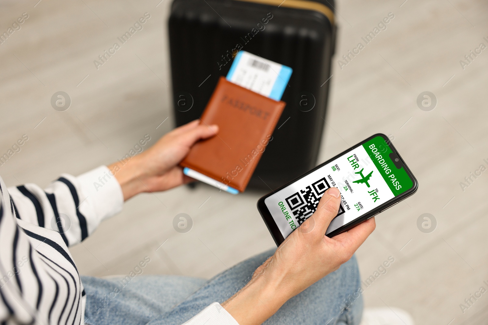 Image of Tourist with passport, flight ticket and mobile phone indoors, above view. Online ticket with QR code on device screen