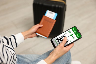 Image of Tourist with passport, flight ticket and mobile phone indoors, above view. Online ticket with QR code on device screen