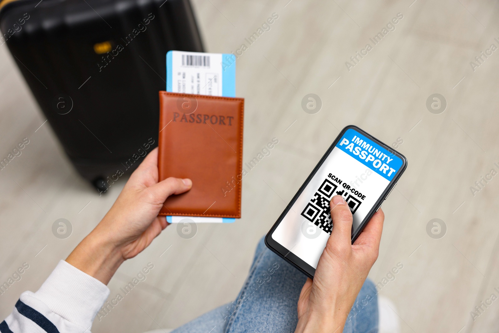 Image of Tourist with passport, flight ticket and mobile phone indoors, above view. Immunity passport app with QR code on device screen