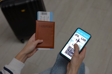 Image of Tourist with passport, flight ticket and mobile phone indoors, above view. Online ticket with QR code on device screen