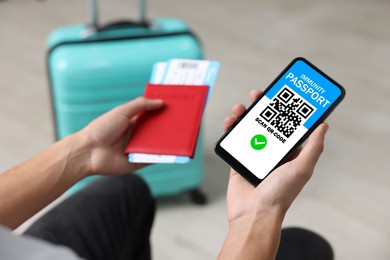 Image of Tourist with passport, flight tickets and mobile phone indoors, above view. Immunity passport app with QR code on device screen